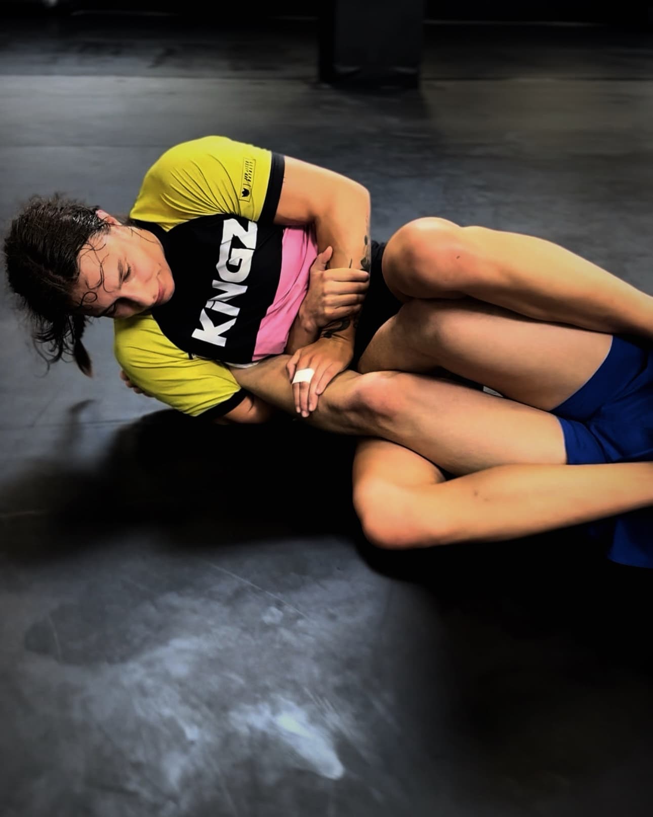 Bodenkampf auf der Matte: Eine Person im Rashguard umklammert das Bein des Trainingspartners, BJJ-Training im Amrani Palace Oberhausen
